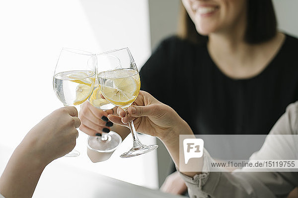 Nahaufnahme von drei Frauen die auf ein Glas Wasser anstoßen