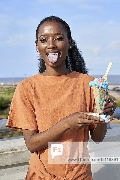 Porträt einer jungen Frau mit hellblauer Eisschaufel mit Zunge