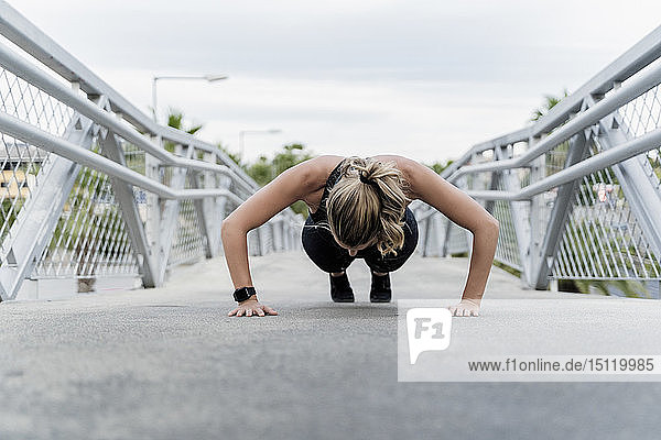 Sportliche Frau macht Push-ups  trainiert auf einer Brücke
