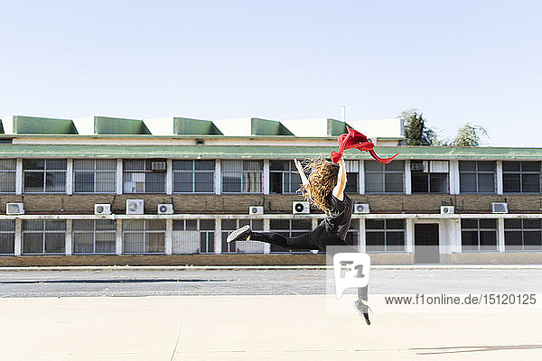 Teenage girl jumping outdoors with red cloth