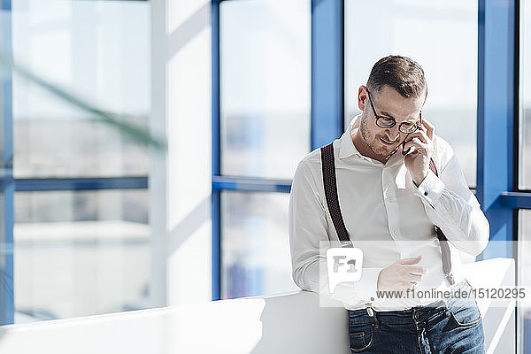 Businessman talking on cell phone at the window in modern office