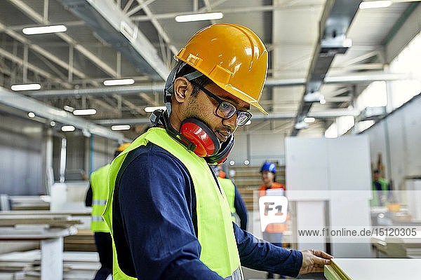 Worker examining wooden board in factory