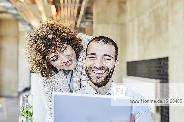 Glücklicher Mann und Frau teilen sich ein Tablett in einem modernen Büro