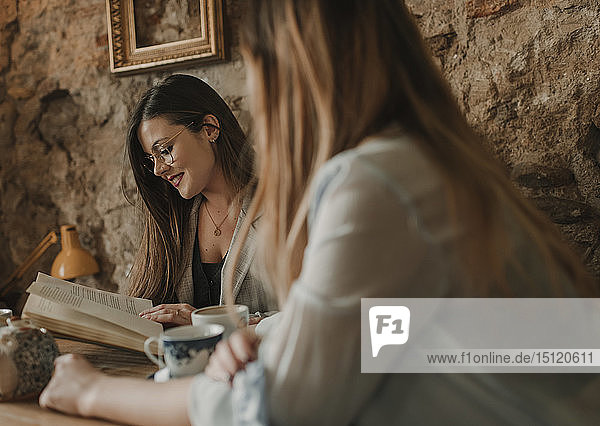 Zwei junge Frauen mit Buch in einem Cafe