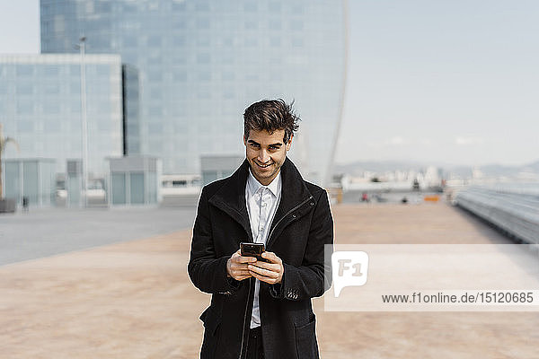 Portrait of smiling businessman holding cell phone in the city