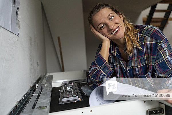 Porträt einer glücklichen jungen Frau mit Montageanleitung in der Küche