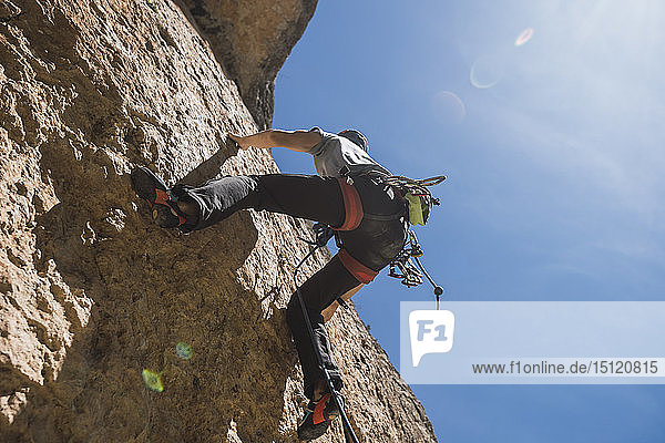 Mann klettert in Felswand
