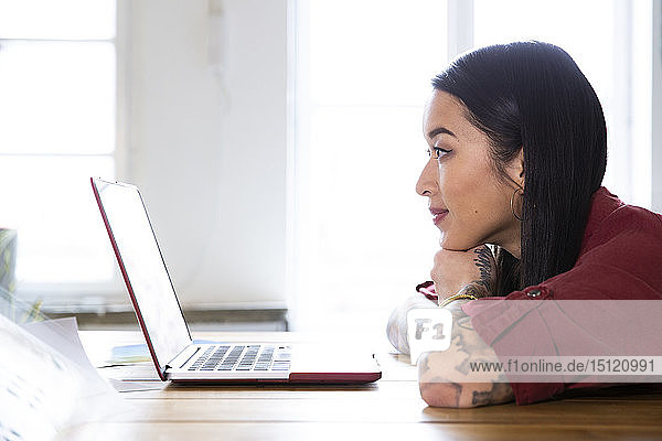 Woman using laptop at table in office