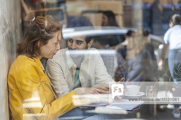 Man and woman with cell phone and notebook meeting in a cafe
