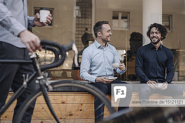 Freunde sitzen vor dem Kaffeehaus unterhalten sich trinken Kaffee