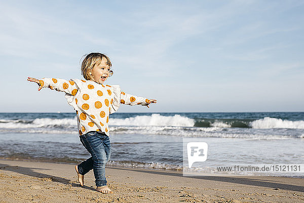 Glückliches kleines Mädchen läuft barfuss am Strand