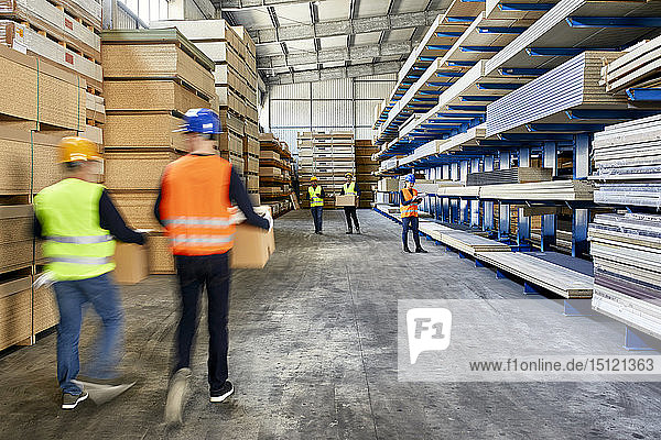 Workers moving and carrying boxes in factory warehouse