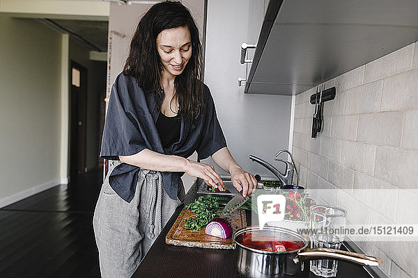 Lächelnde Frau bereitet in der Küche Salat zu