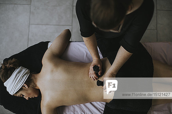 Young woman with sachets on her back during stamp massage