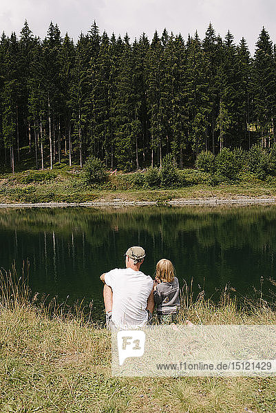Vater und Tochter am Seeufer sitzend  Jochberg  Österreich