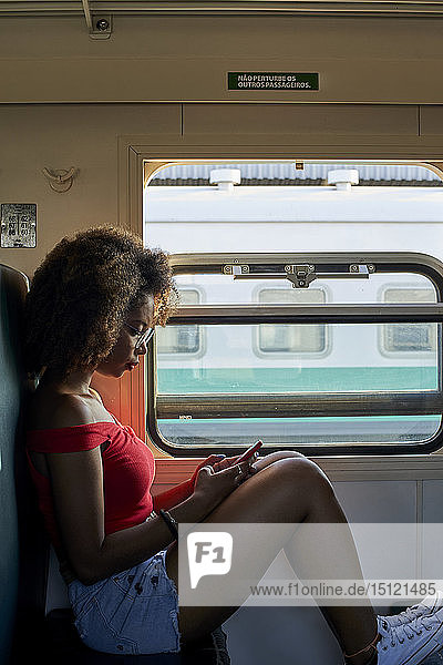 Junge Frau im Zug beim Überprüfen ihres Telefons