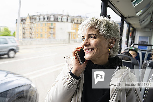 Frau sitzt im Bus und spricht mit dem Smartphone