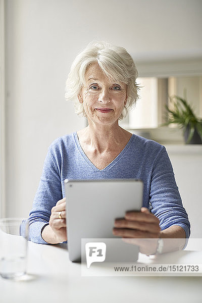 Porträt einer lächelnden  reifen Frau mit digitalem Tablett am Schreibtisch