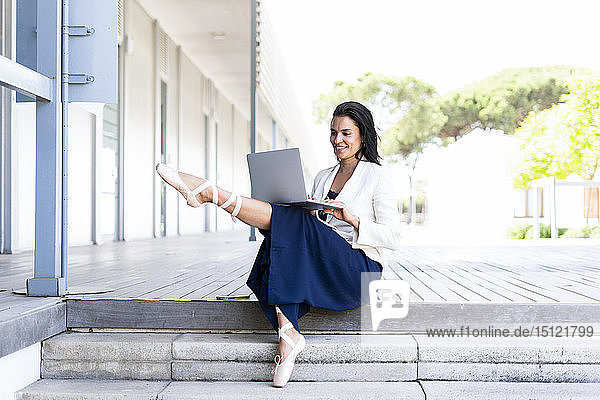 Balletttänzerin mit Laptop auf Stufen sitzend