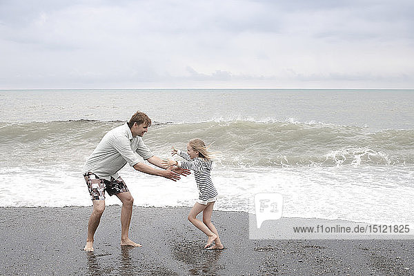 Vater spielt mit seiner Tochter am Strand