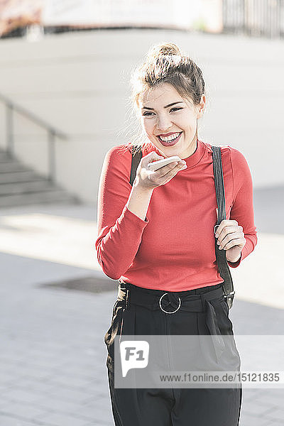 Happy young woman using smartphone in the city