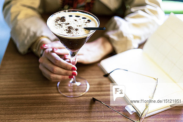 Nahaufnahme einer Frau mit einem Kaffee-Cocktail in einem Cafe