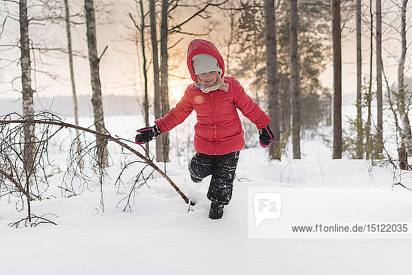 Finnland  Kuopio  glückliches Kleinkind läuft bei Sonnenuntergang in Winterlandschaft