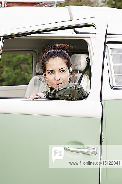 Young woman sitting in camperm looking out of window