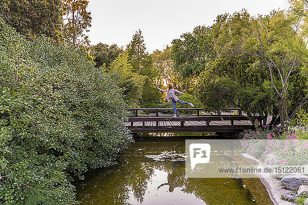 Junge rothaarige Frau balanciert auf einer Brücke in einem Park
