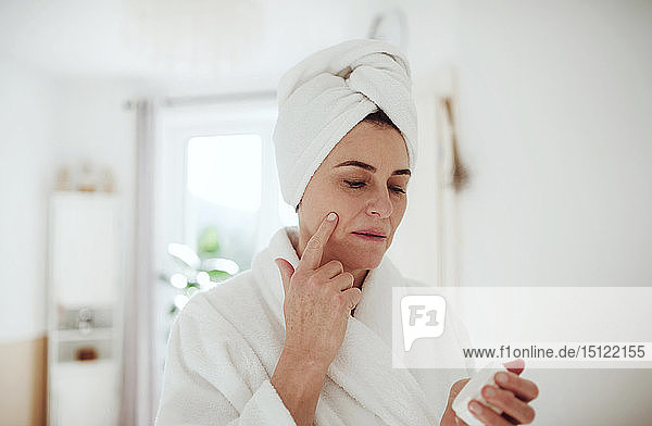 Reife Frau im häuslichen Badezimmer mit Feuchtigkeitscreme