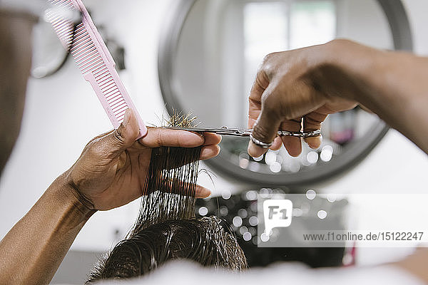 Nahaufnahme eines Friseurs  der die Haare eines Kunden in einem Friseursalon schneidet