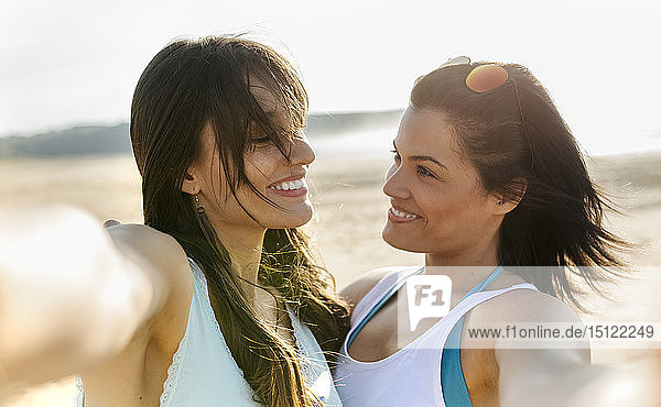 Porträt von zwei glücklichen Freundinnen am Strand