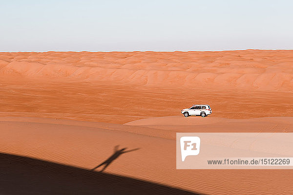 Schatten eines Mannes  der auf den Dünen steht und dem Auto zuwinkt