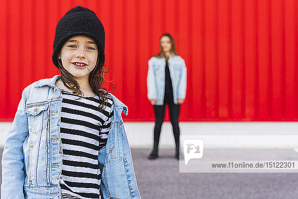 Portrait of little girl with older sister standing in the background
