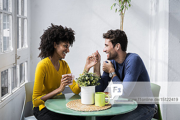 Happy affectionate couple sitting at table at home