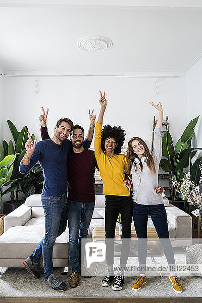Porträt von vier glücklichen Freunden  die nebeneinander im Wohnzimmer stehen