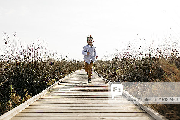 Happy little boy running on boardwalk