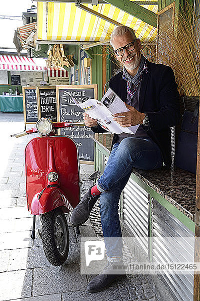 Mature man waiting at the market reading brochure