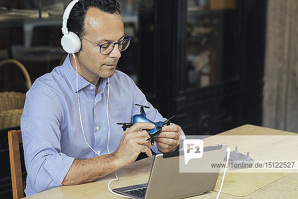 Businessman with headphones  laptop and drone in a coffee shop