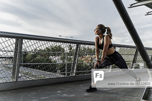 Sportliche Frau wärmt sich auf einer Brücke auf