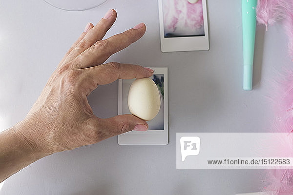 Hand  die ein Ei gegen einen Polaroid-Bilderrahmen hält
