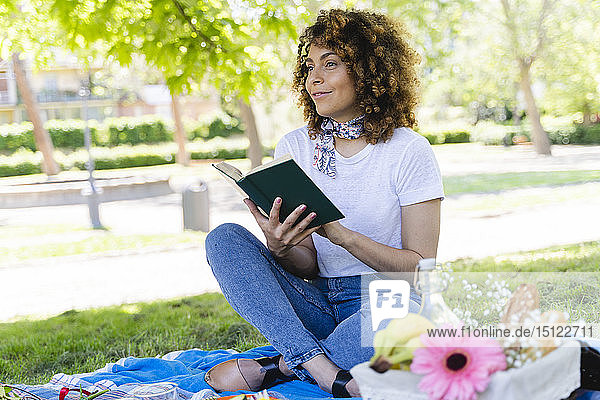 Entspannte Frau mit Buch bei einem Picknick im Park