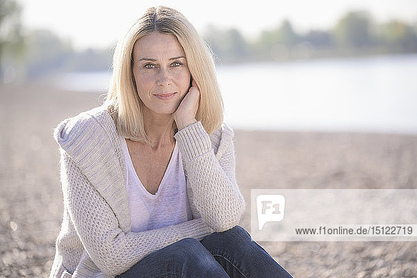 Portrait of smiling mature woman sitting at the riverside