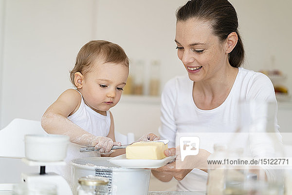 Mutter und kleine Tochter backen zu Hause in der Küche gemeinsam einen Kuchen