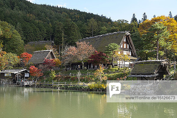 Autumn foliage and traditonal thatched buildings around a lake at Hida Folk Village Hida No Sato Takayama Honshu Japan Asia
