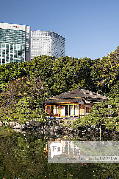 A modern highrise hotel above the Tsubame-no-ochaya a tea house on a lake in the Hama-rikyu Gardens Tokyo Honshu Japan Asia