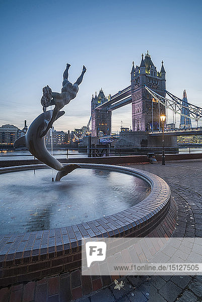 Girl with Dolphin fountain and Tower Bridge at night  St. Katharine's and Wapping  London  England  United Kingdom  Europe