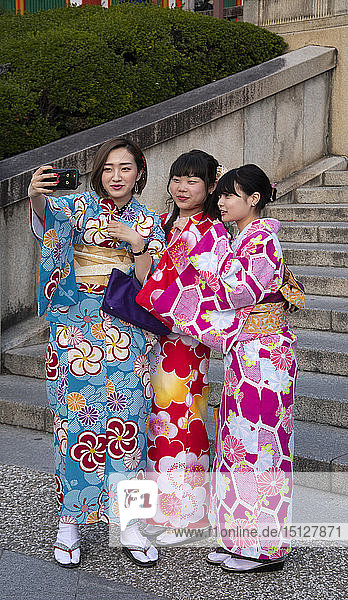Young Japanese women dressed in colourful kimonos taking selfies in Kyoto Japan Asia