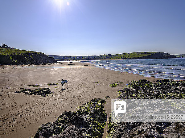 Ein Surfer geht an einem sonnigen Morgen in Bigbury-on-Sea  Devon  England  Vereinigtes Königreich  Europa  zu seiner Session.