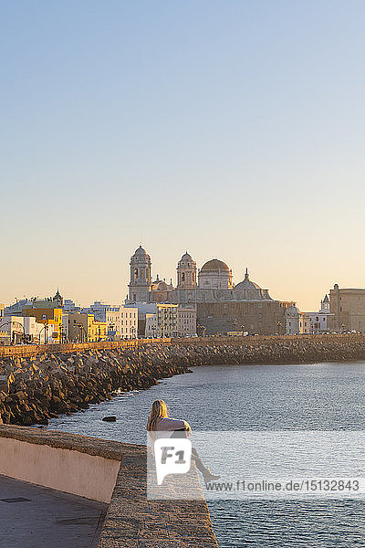 Frau genießt den Blick auf die Kathedrale von Santa Cruz und das Meer von der Uferpromenade aus gesehen  Cadiz  Andalusien  Spanien  Europa